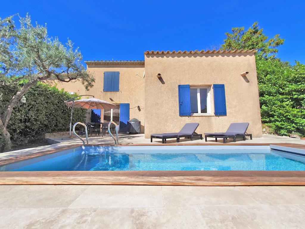 a swimming pool with two chairs and a house at Maison du Chat in Bargemon