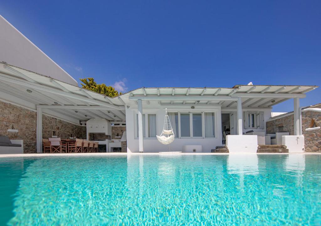 a swimming pool with a pergola and a house at Villa Harmony in Kalafatis