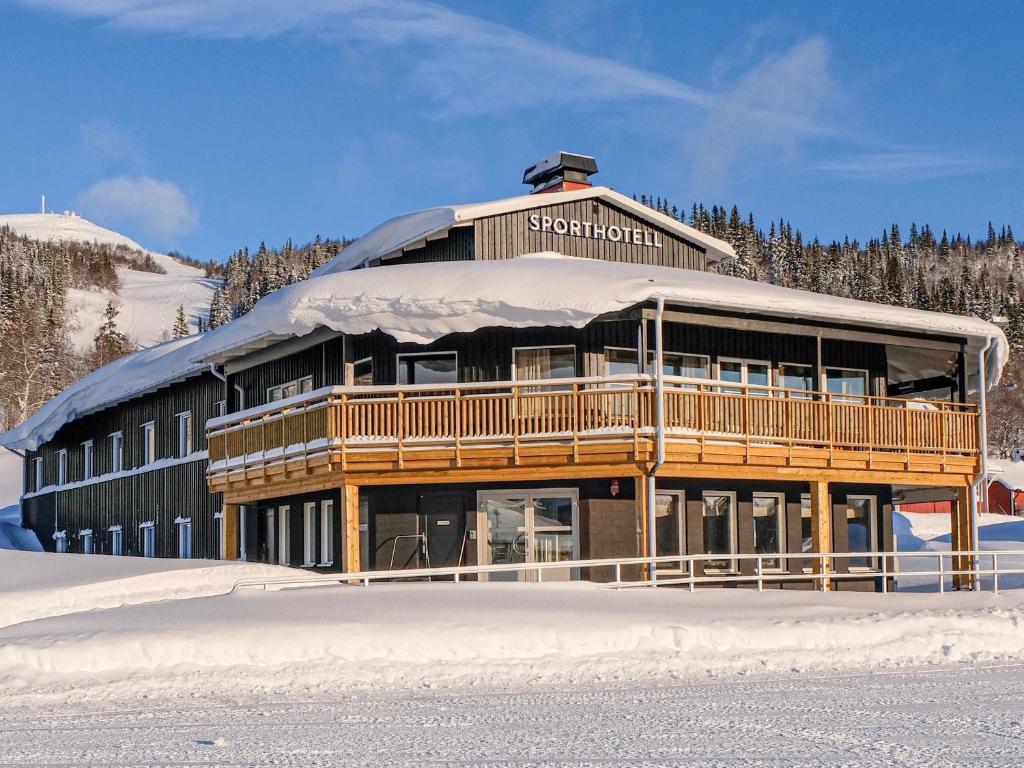 un gran edificio de madera con nieve en el suelo en Tärnaby Sporthotell en Tärnaby