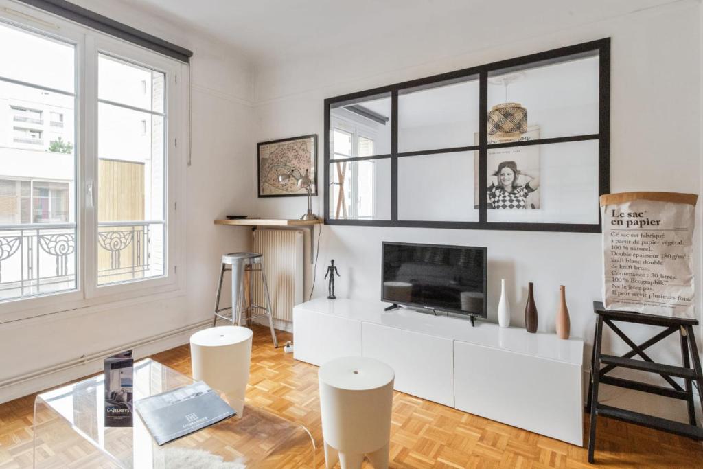 uma sala de estar com uma televisão num armário branco em Chic 1br near Paris and the Bois de Vincennes in Saint-Mandé Welkeys em Saint-Mandé