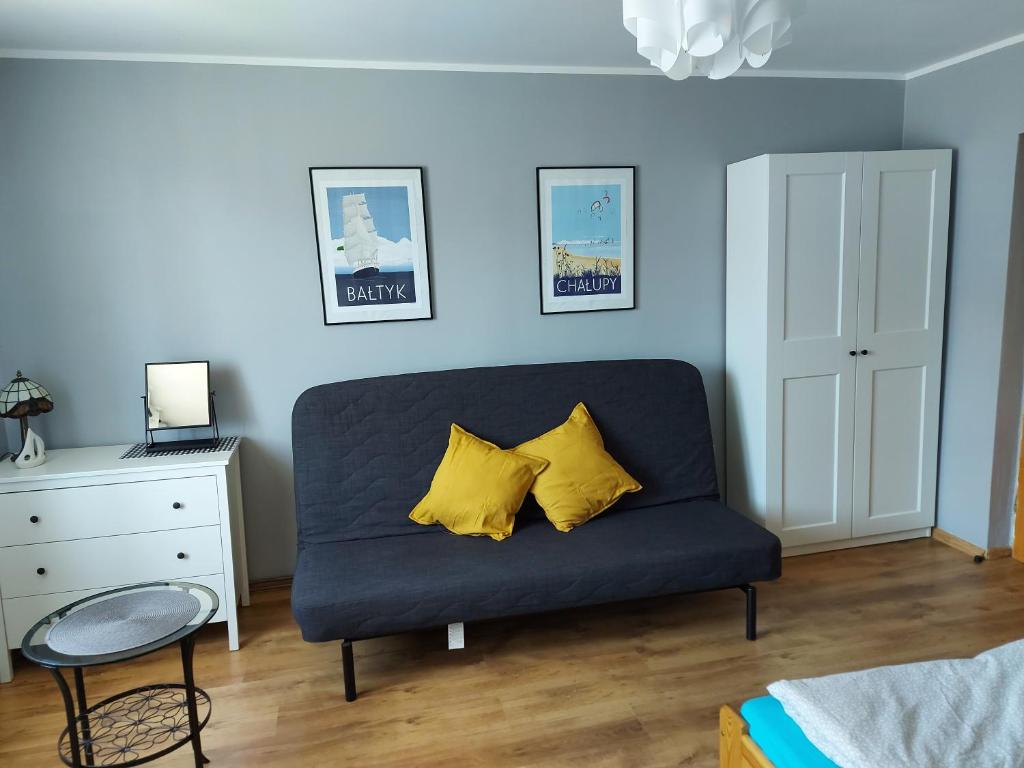 a blue couch with two yellow pillows in a bedroom at Apartament wakacyjny Chałupy in Chałupy