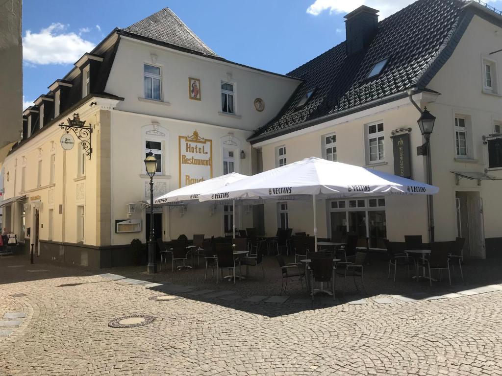 a group of buildings with chairs and umbrellas on a street at Hotel Rauch in Attendorn