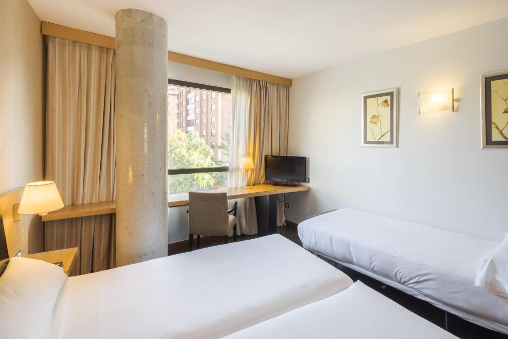 Una habitación de hotel con dos camas y un escritorio. en RICE Bulevar, en Burgos