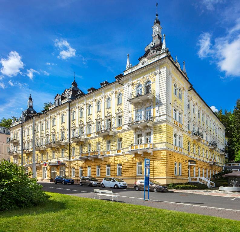 a yellow building with cars parked in front of it at Reitenberger Spa Medical in Mariánské Lázně