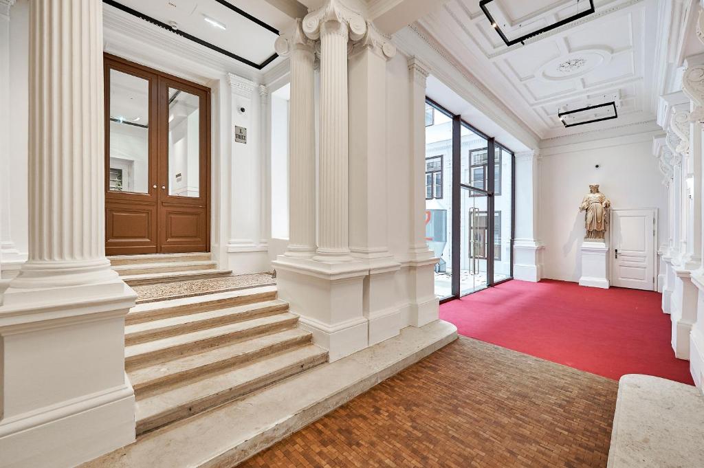 um grande corredor com colunas brancas e um tapete vermelho em Herzfeld Arthaus Vienna Premium Apartments em Viena