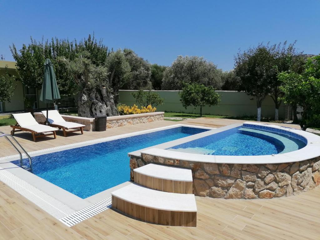 una piscina con una pared de piedra y un patio con sillas en Villa MATA - 600m² with Private Pool and Jacuzzi, en Kalithies