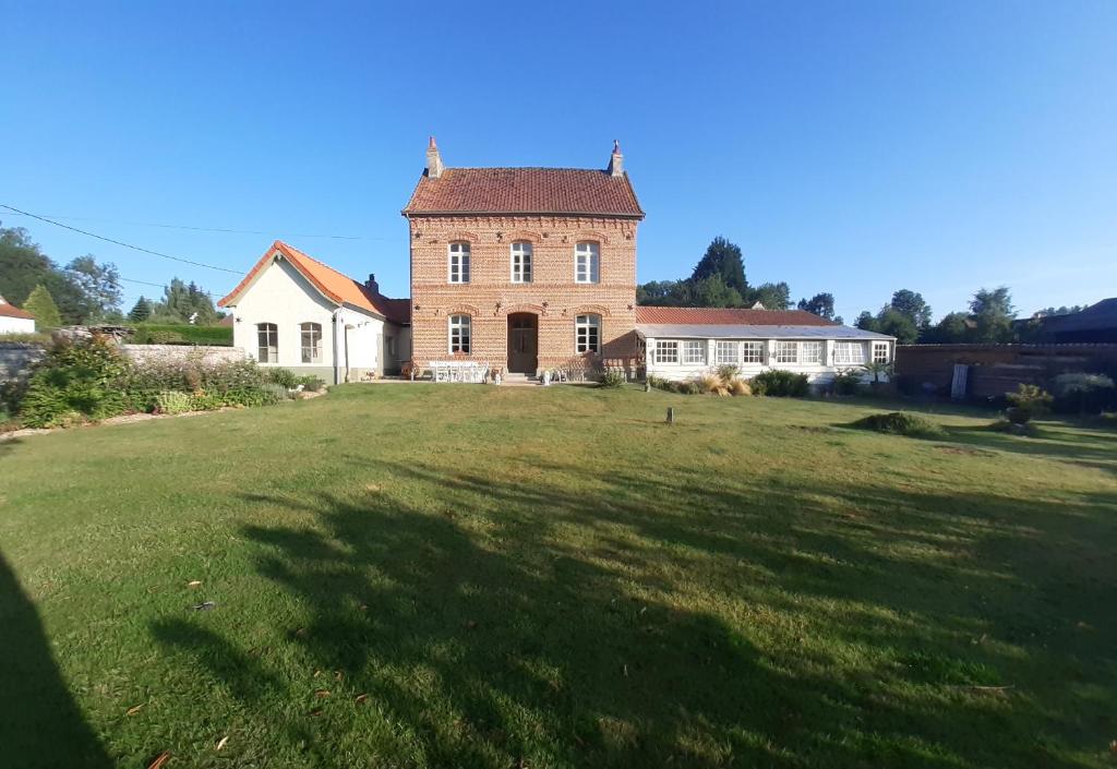 una antigua casa de ladrillo con un gran campo de césped en Le presbytère de Fressin, en Fressin