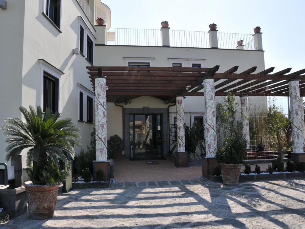 a large white building with a wooden archway at Costa Hotel in Pompei