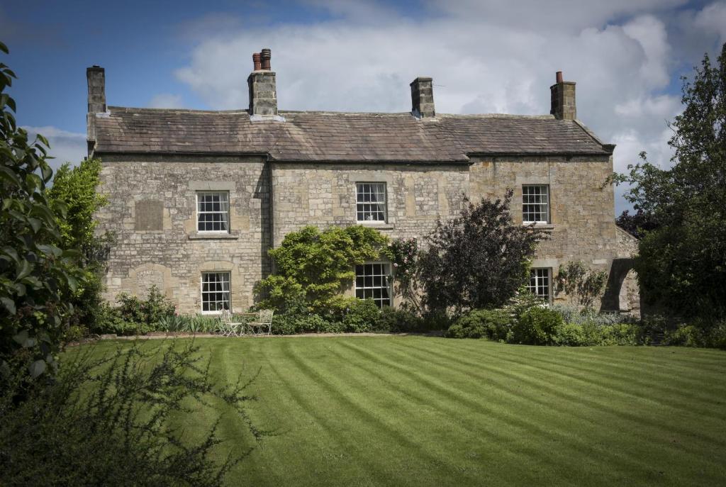 una antigua casa de piedra con un gran césped delante en Mallard Grange B&B, en Ripon