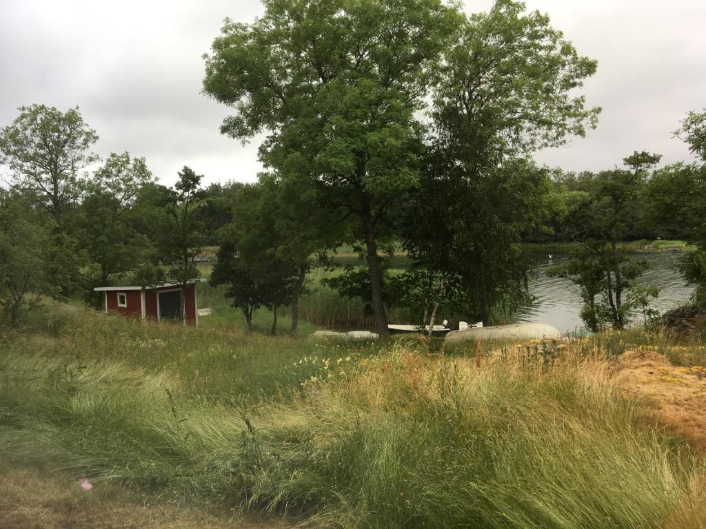 uma pequena cabana vermelha num campo ao lado de um lago em Hotell Gullvivan em Brändö