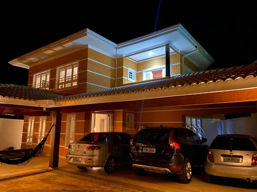 two cars parked in front of a house at night at Casa de Campo Alto Padrao in Piracaia