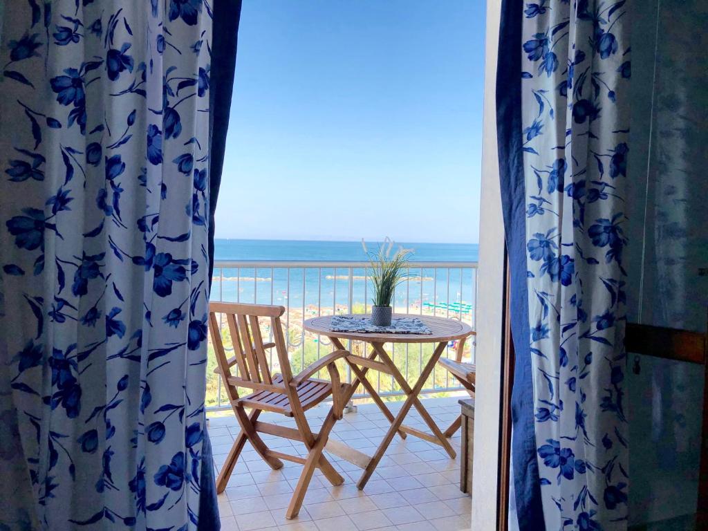 een tafel en stoel op een balkon met uitzicht op de oceaan bij Casa Confalonieri fronte mare con vista mozzafiato in San Benedetto del Tronto