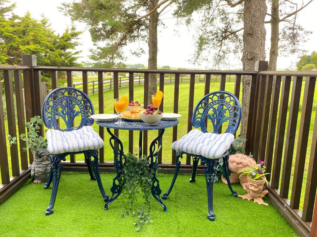 einen Tisch und zwei Stühle mit einer Schüssel Essen auf einer Terrasse in der Unterkunft Lake District romantic get away in 1 acre gardens off M6 in Penrith