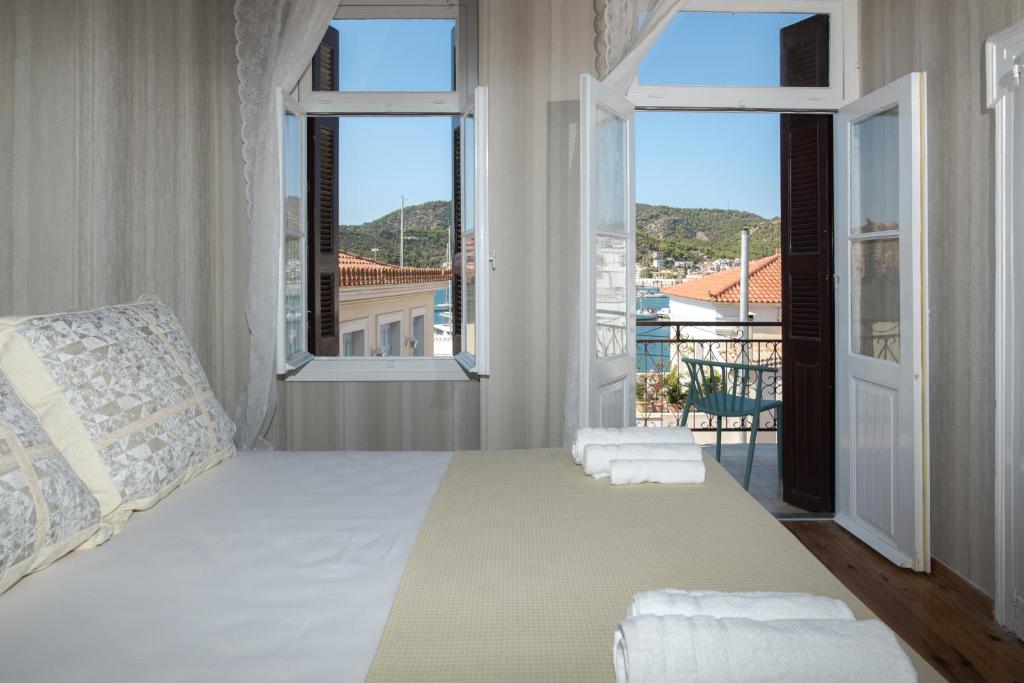 1 Schlafzimmer mit einem großen Bett und 2 Fenstern in der Unterkunft Neoclassical manor house in Poros