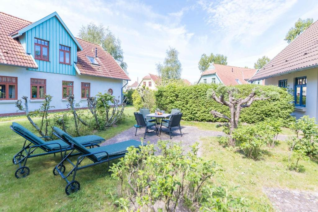 a patio with a table and chairs in a yard at Ferienhaussiedlung Strandperlen Sanddornhof 5b (Typ V) in Wustrow