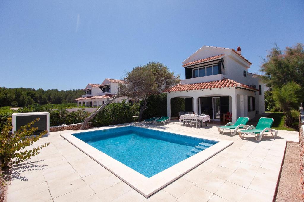 Villa con piscina frente a una casa en Villa ELSIE en Arenal d'en Castell