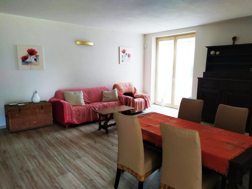 un soggiorno con tavolo e divano rosso di Appartamento Corte dei Landi a Cavriago