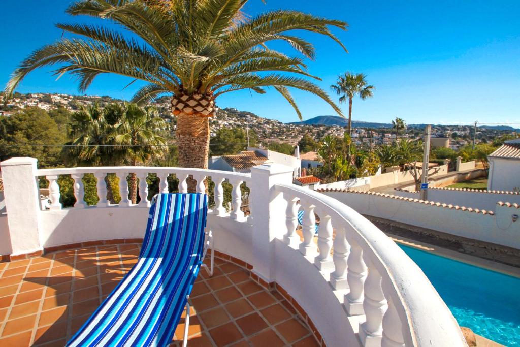 a blue and white chair on a balcony with a palm tree at El Bruni - modern villa close to the beach in Benissa in Pedramala