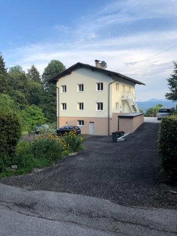 una gran casa blanca con techo negro en Velden View Ferienwohnung direkt am Wald mit großer Sonnenterrasse und grandiosem Karawankenblick, en Velden am Wörthersee