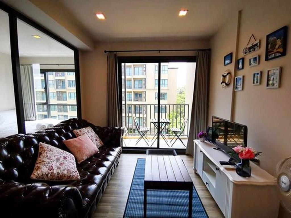 sala de estar con sofá de cuero y ventana grande en Rain Cha-am Huahin, en Cha Am