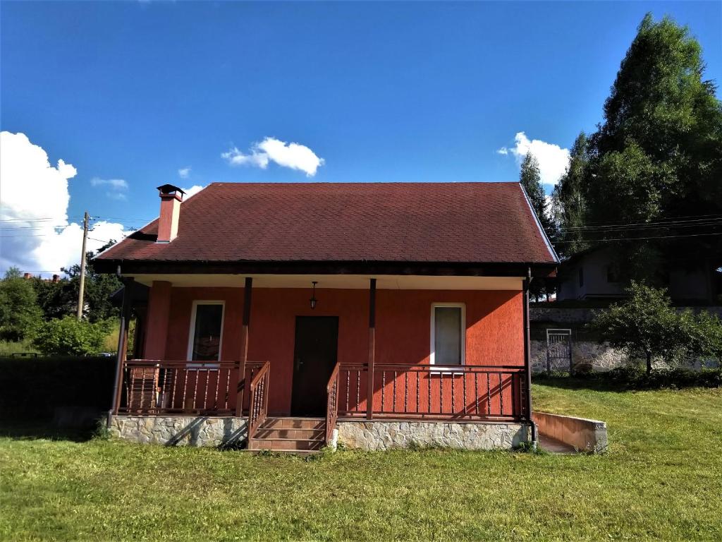 a small red house with a porch on a field at VILLA IRINA - Govedartsi in Govedartsi