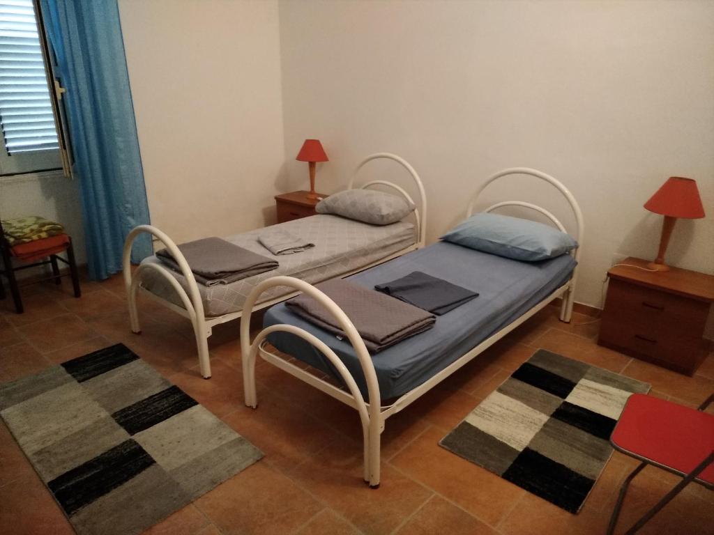 two beds in a room with two chairs and a table at trivanio semplice in Sassari