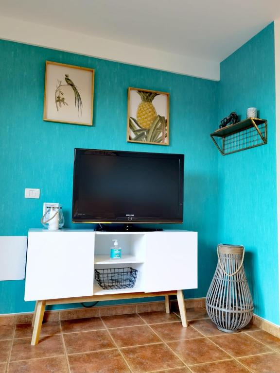 a living room with a tv on a blue wall at Nautilus I: Casa con terraza y vistas al mar in La Caleta