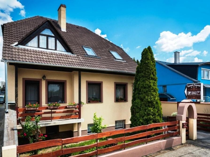 dom z brązowym dachem i płotem w obiekcie Szenti Vendégház w Győr