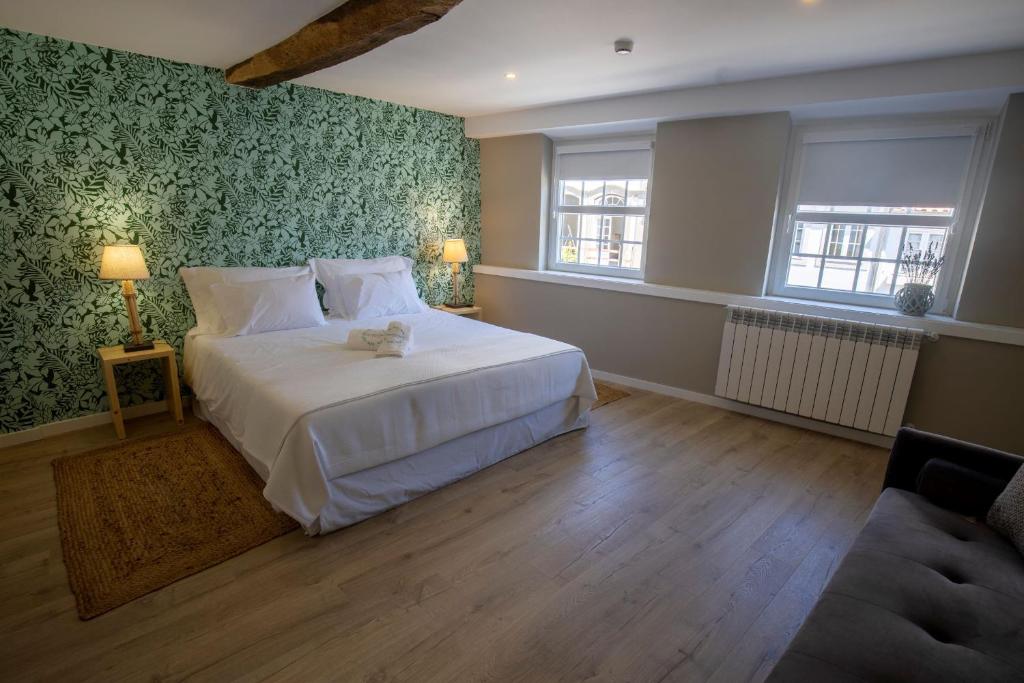 Un dormitorio con una gran cama blanca con papel pintado verde en Secret Garden Suites in Bragança, en Bragança