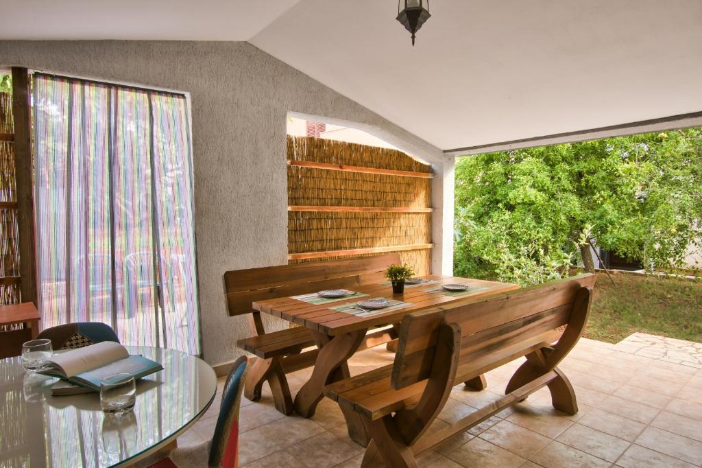 a dining room with a wooden table and a window at Apartman Tanja in Fažana