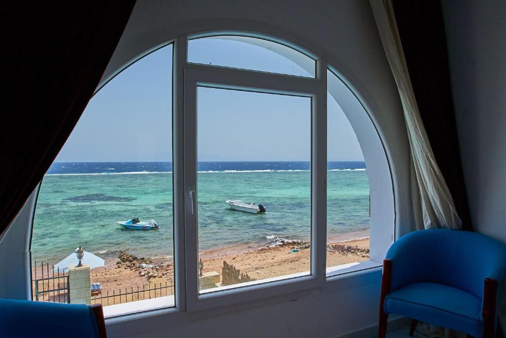 una ventana con vistas a una playa con barcos en el agua en Solaris en Dahab