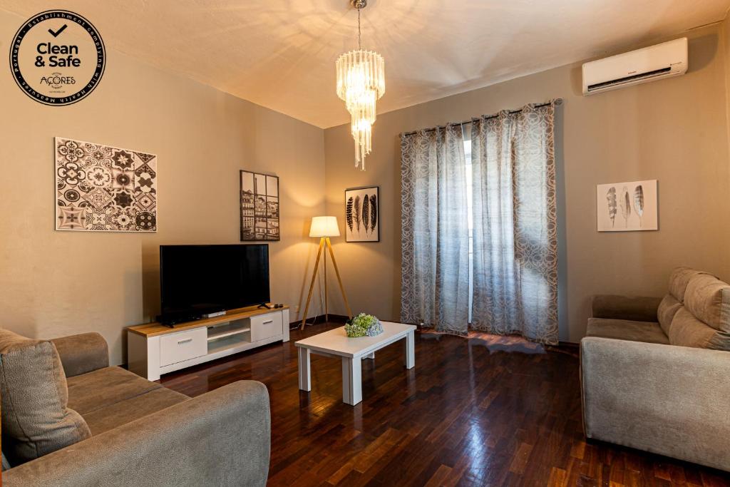 a living room with a couch and a tv at Casa do Pescador SBMP-1 in Fayal da Terra