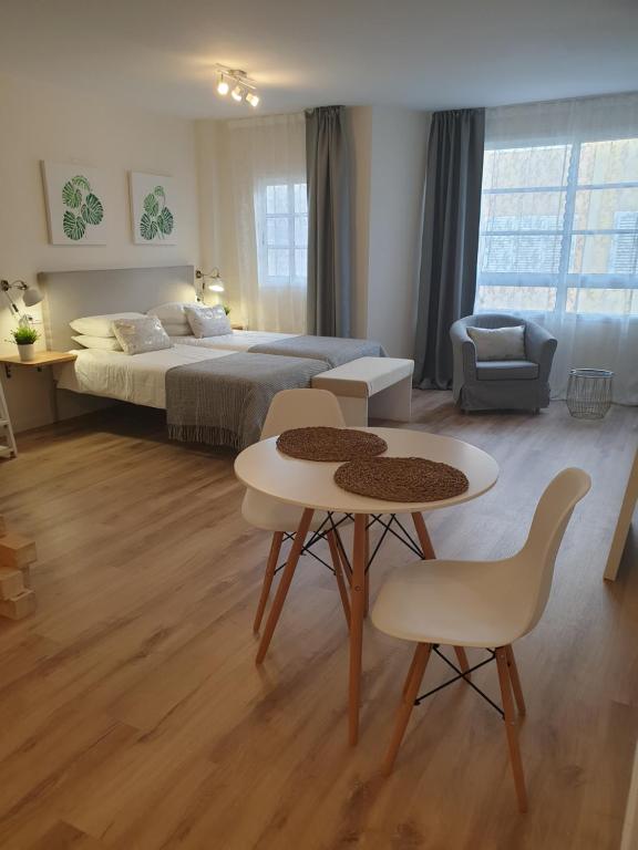 1 dormitorio con 1 cama, mesa y sillas en Morrojable Luxury Beach Apartments en Morro del Jable