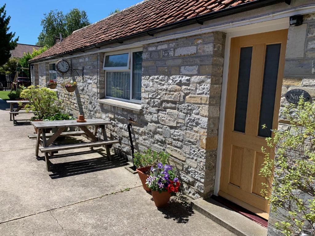 a stone house with a wooden door and a picnic table at No. 4 Smith Cottages in Langport
