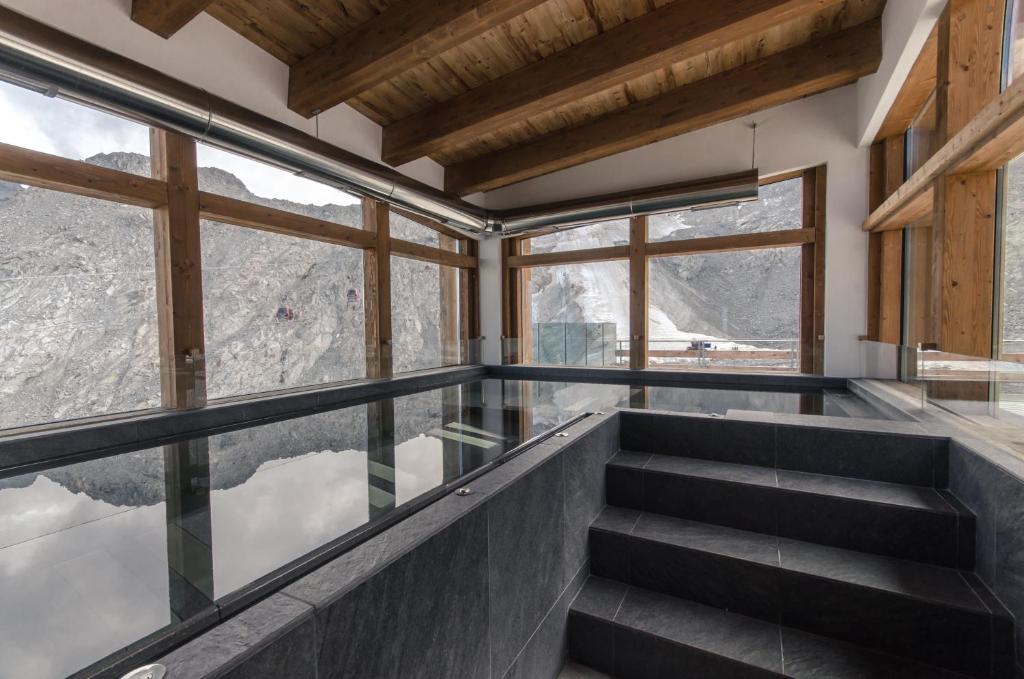 a glass balcony with stairs and a view of the mountains at CAPANNA PRESENA in Passo del Tonale