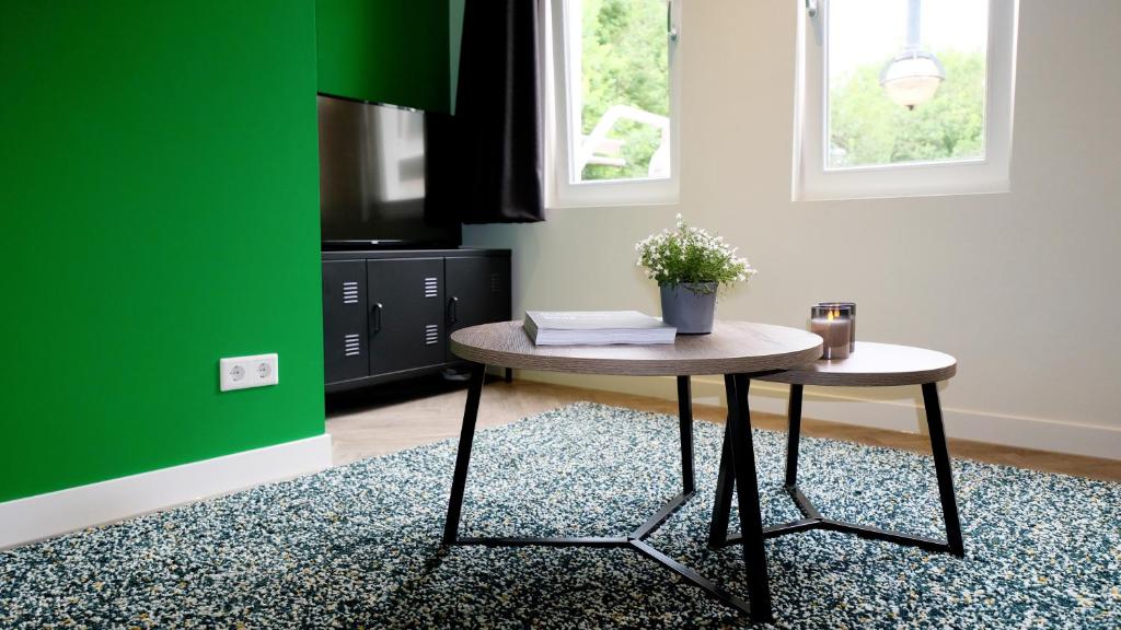 a living room with a table and a green wall at Luxury 60m2 Apartment with 20m2 Private Terrace in Eindhoven