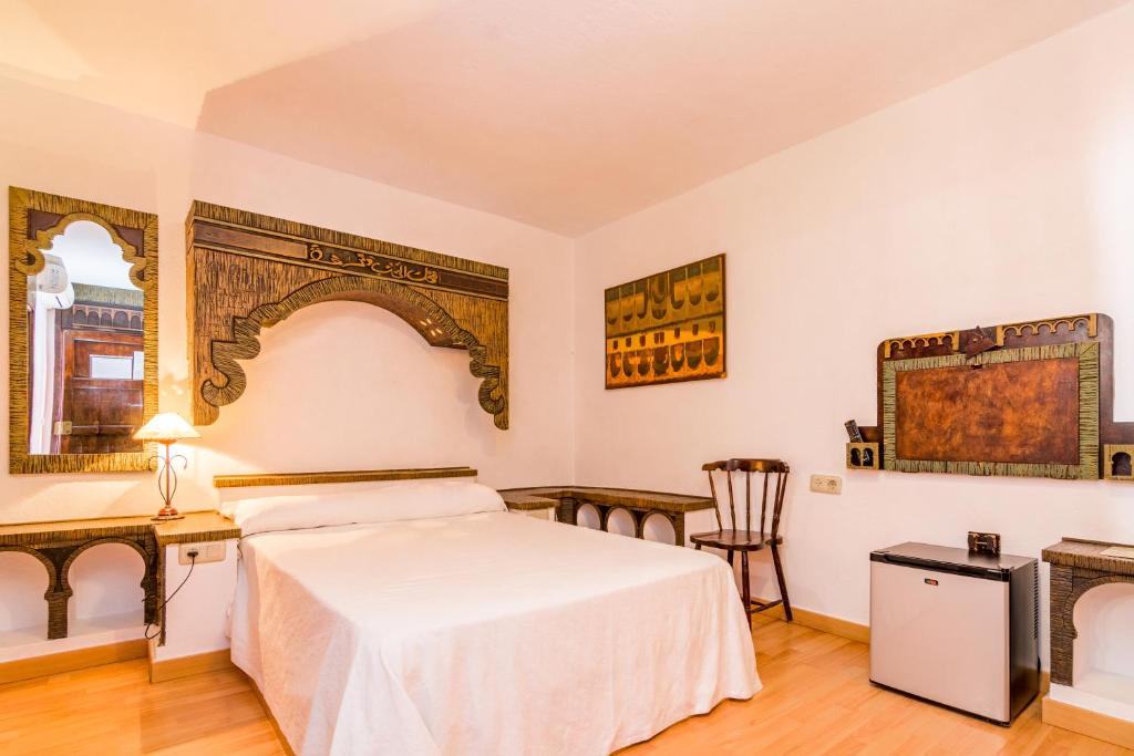 a bedroom with a bed and a desk and a chair at Hostal Alhambra in Zahora