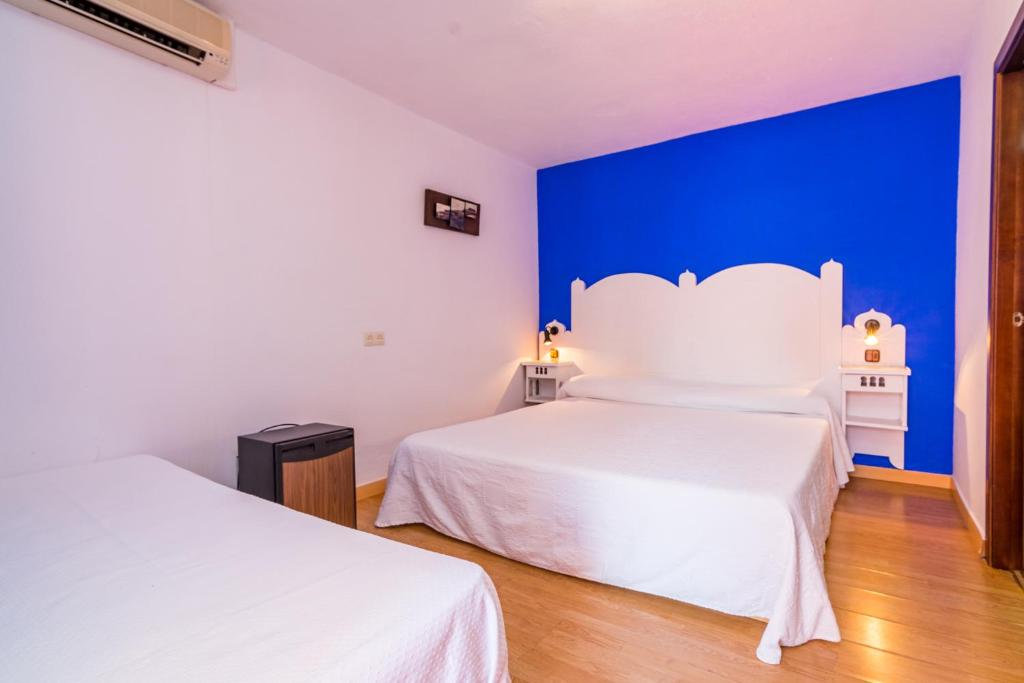 a bedroom with two beds and a blue wall at Hostal Alhambra in Zahora