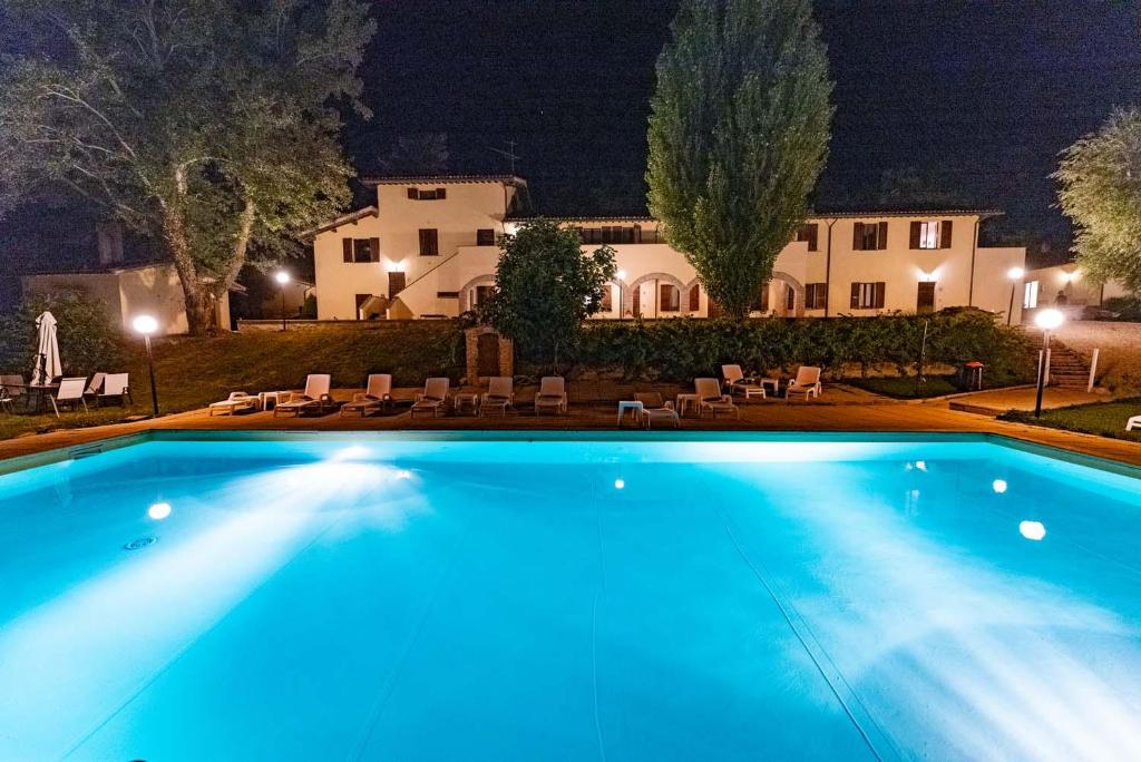 a swimming pool in front of a house at night at Abadia Farneto in Gubbio