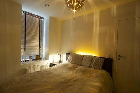 a bedroom with a bed and a window and a light at Cozy and silent ground floor apartment in Copenhagen