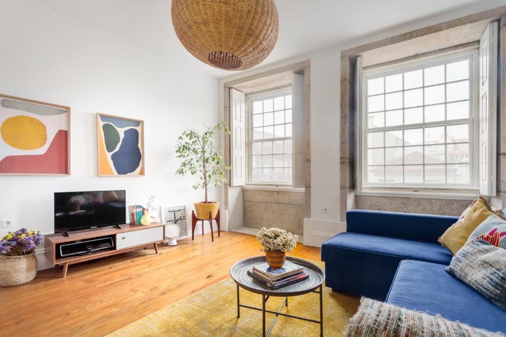 sala de estar con sofá azul y TV en Own Places Clérigos Apartments, en Oporto