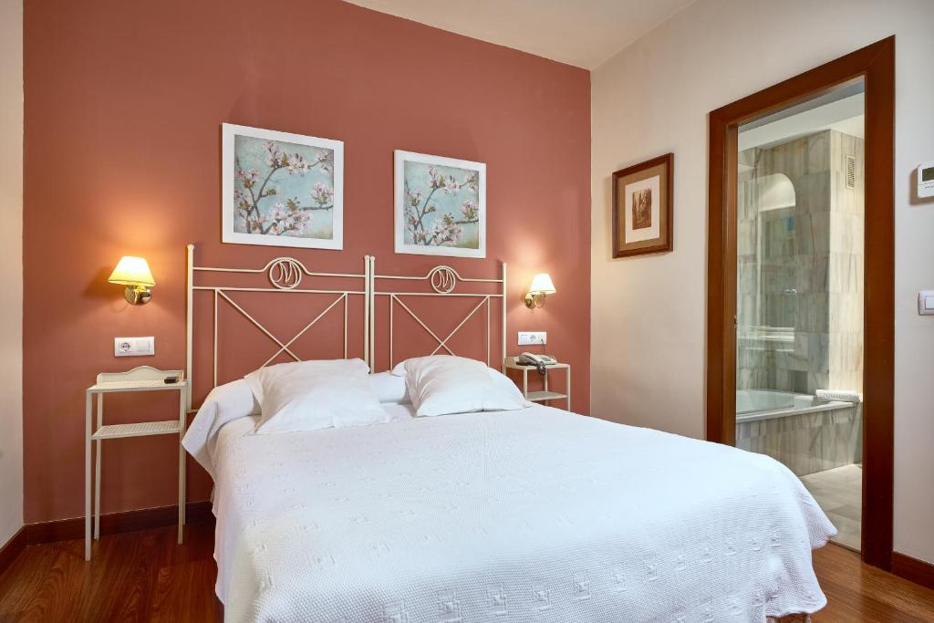 a bedroom with a white bed and white walls at Hotel Murillo in Seville