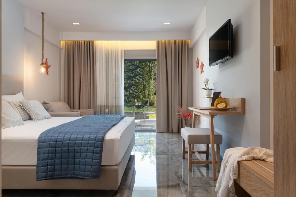 a hotel room with a bed and a table and a desk at Notia Luxury Living in Porto Koufo