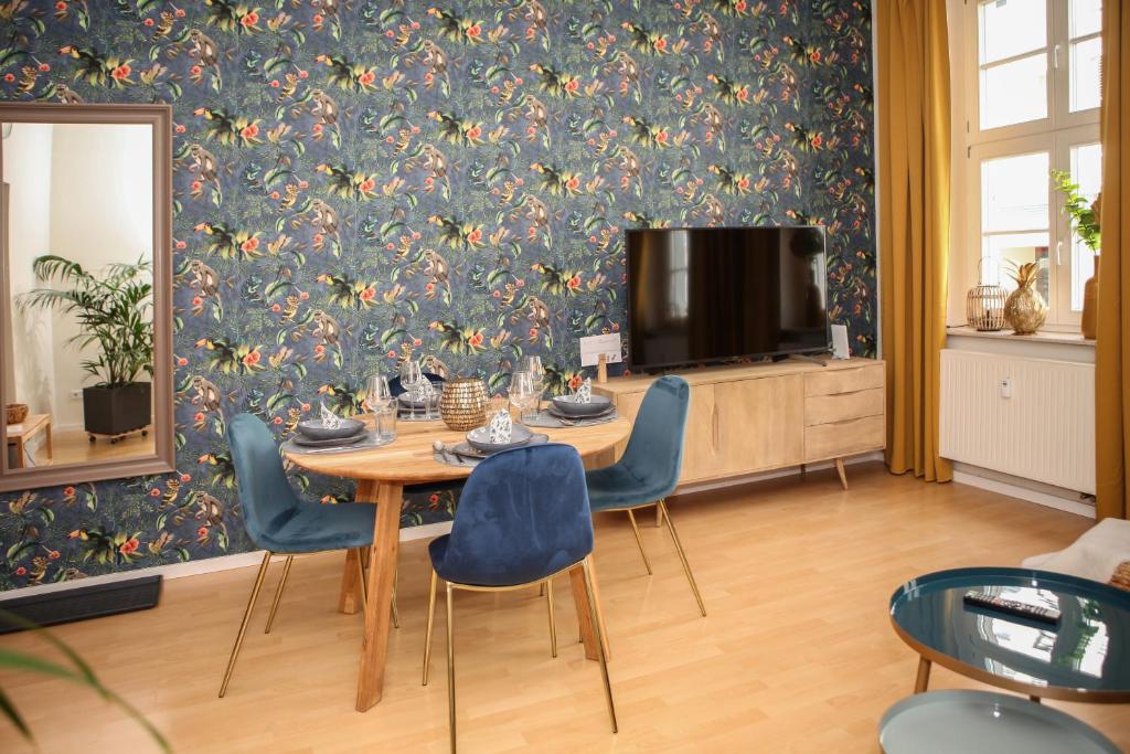 una sala da pranzo con tavolo, sedie e TV di Sleepwell Apartment - Emilienblick a Lipsia