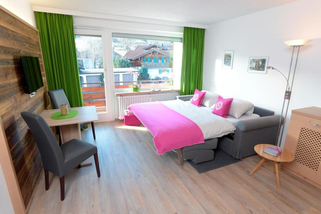 a bedroom with a bed and a couch and a table at Appartement „Klein & Fein“ in Bolsterlang