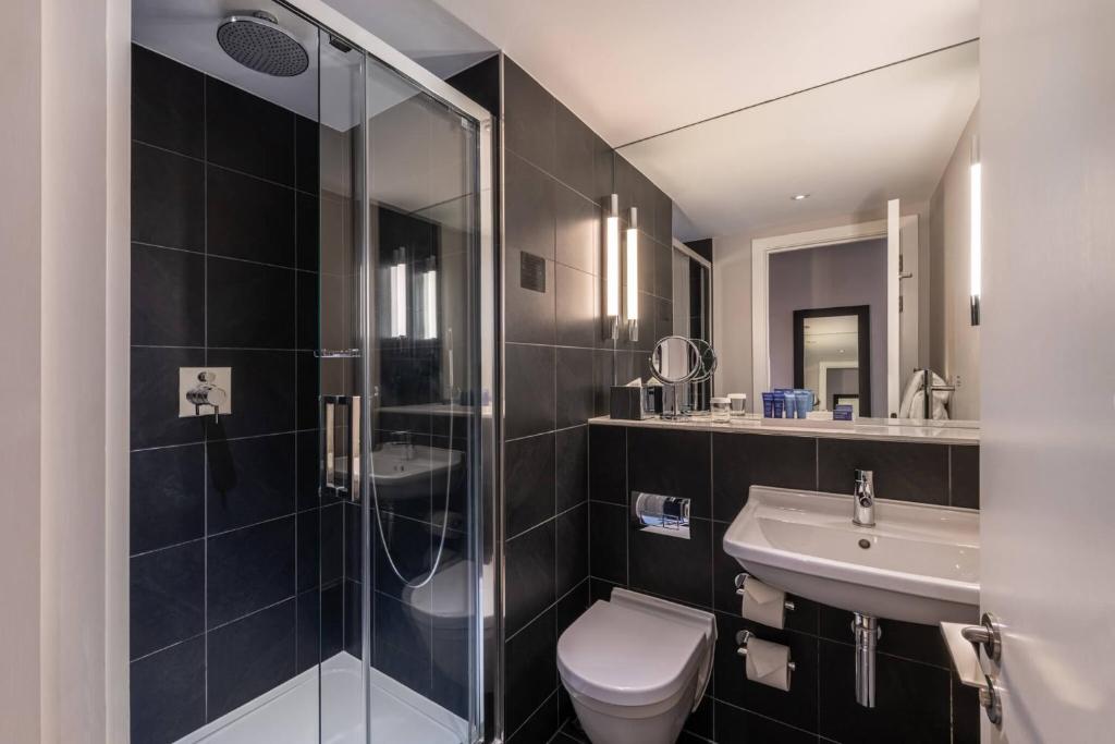 a bathroom with a shower and a toilet and a sink at The Resident Soho in London