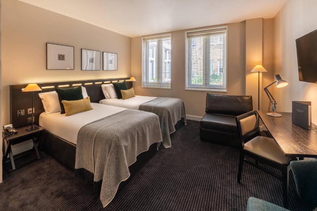 a hotel room with two beds and a chair at The Resident Soho in London