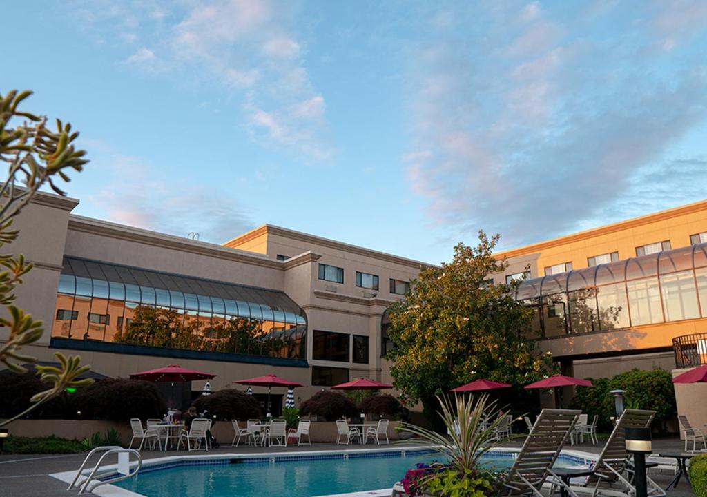 a hotel with a pool and tables and chairs at Monarch Hotel & Conference Center in Clackamas