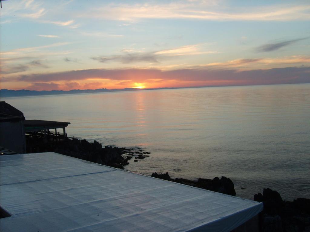einen Sonnenuntergang über einem Wasserkörper mit einem Dock in der Unterkunft Ammaresiamo LTB in Cefalú
