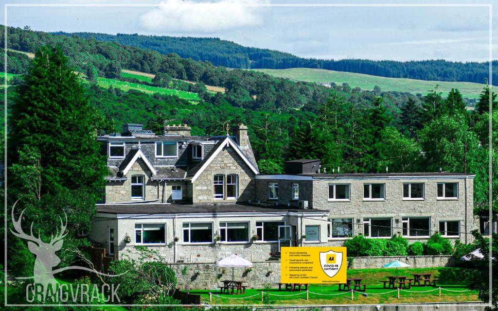 a large house with a yellow sign in front of it at Craigvrack Hotel & Restaurant in Pitlochry